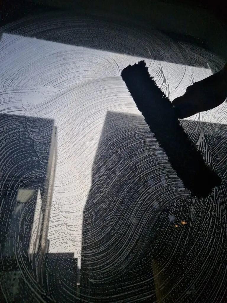 Ikkunanpesua Helsingissä laadukkailla työvälineillä, taustalla korkeat kerrostalot